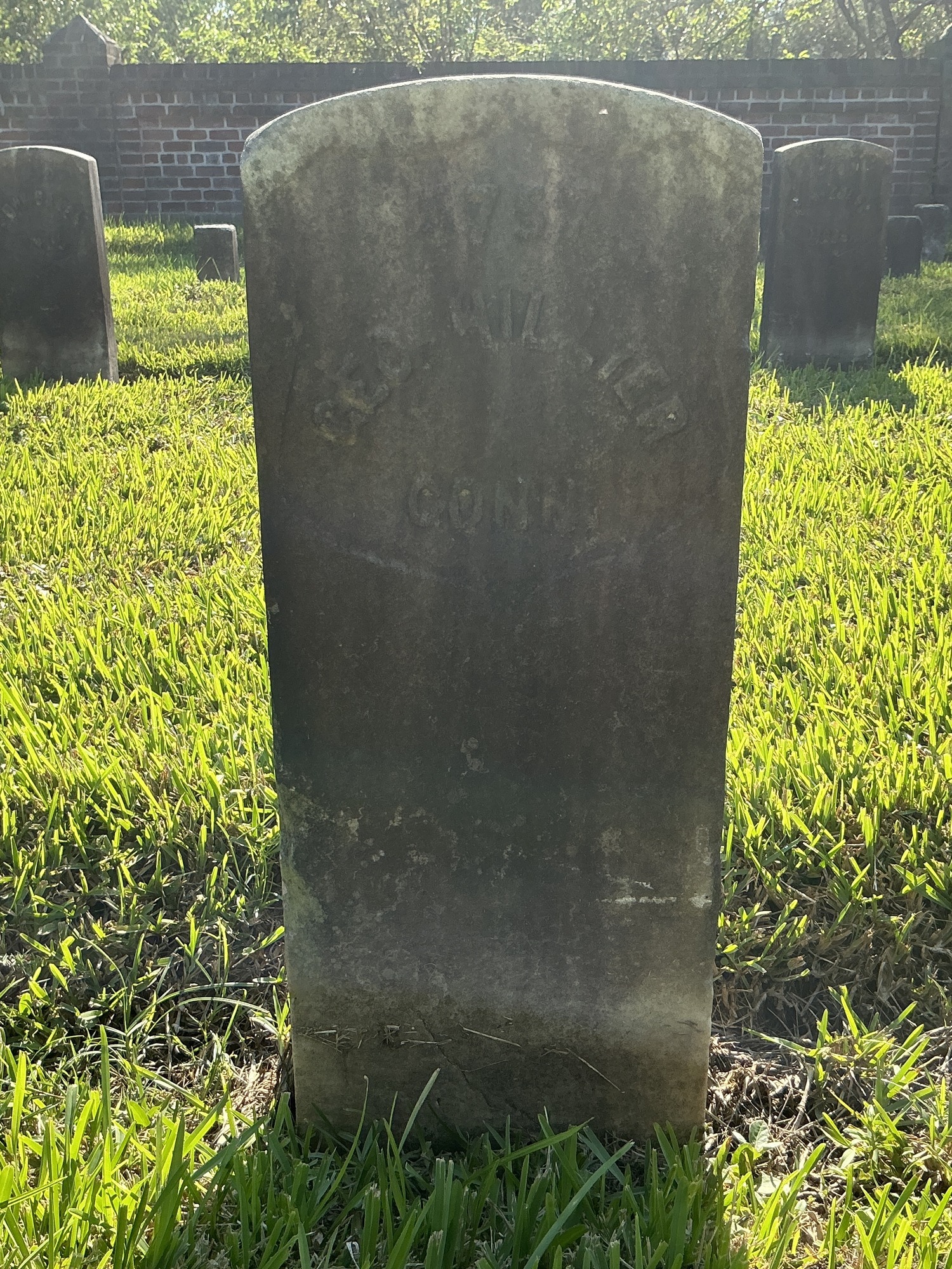 Front of historic upright marble headstone with recessed shield face.