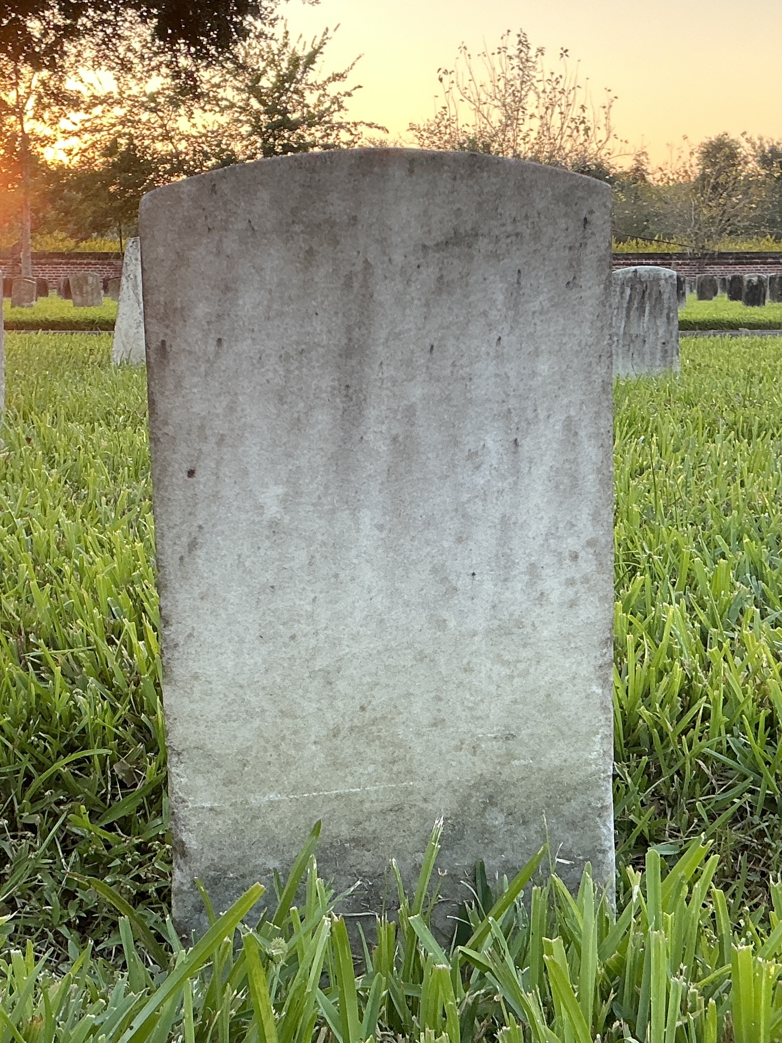 Back of historic upright marble headstone with recessed shield face.