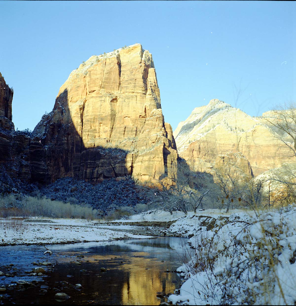 View of Angels Landing from canyon floor, snow along banks of the Virgin River.
