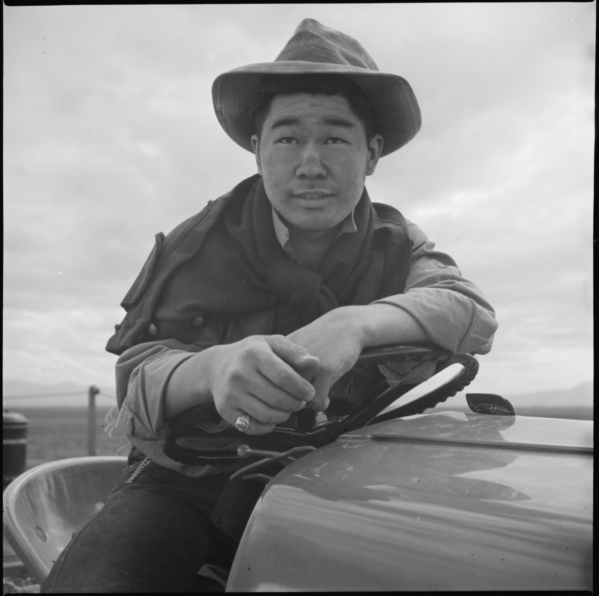 Jimmy Inahara, 24, farmer-evacuee from Stockton, California, operates a tractor on the farm at this War Relocation Authority Center for evacuees of Japanese ancestry