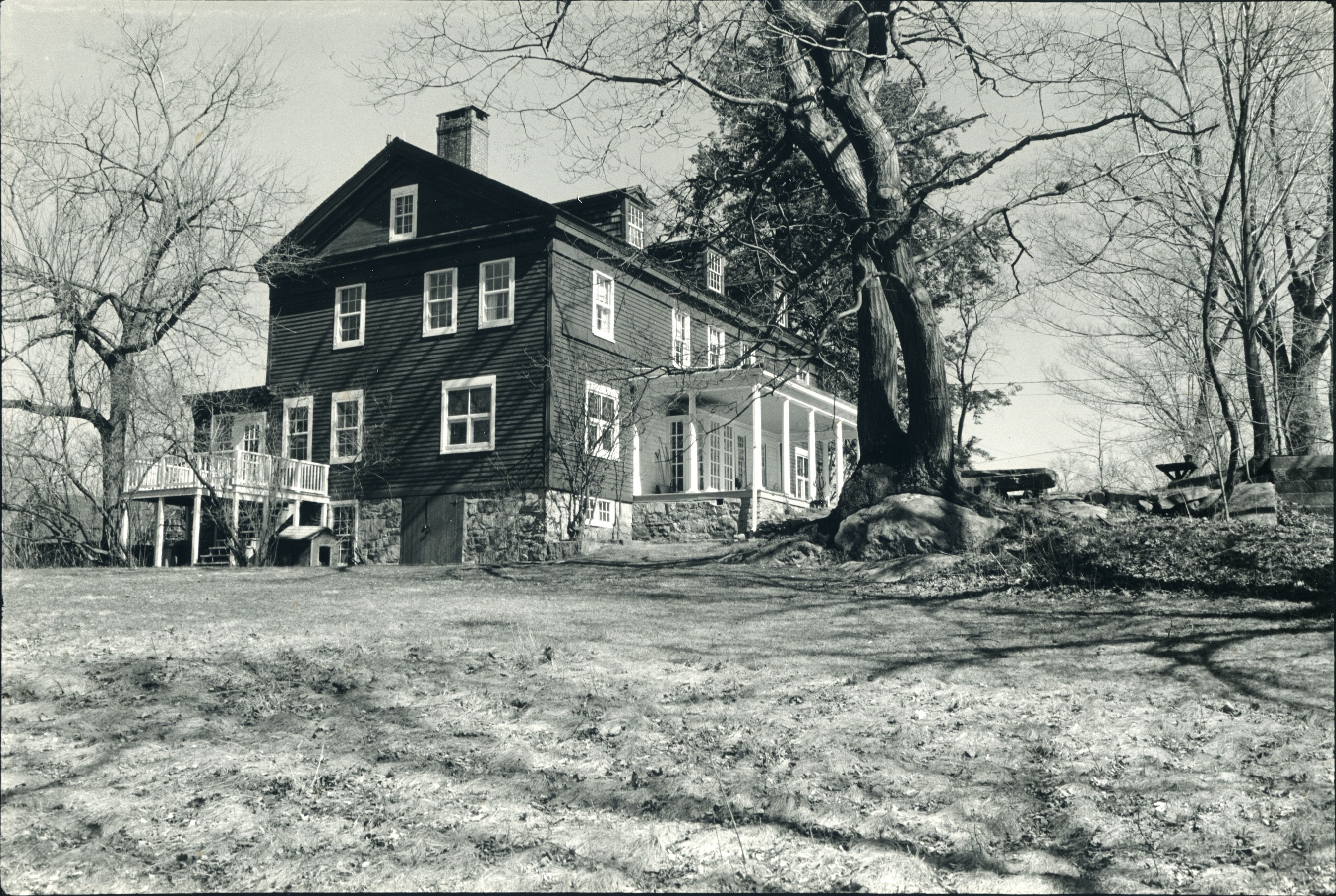 A black and white photograph of a two story building with a front porch.