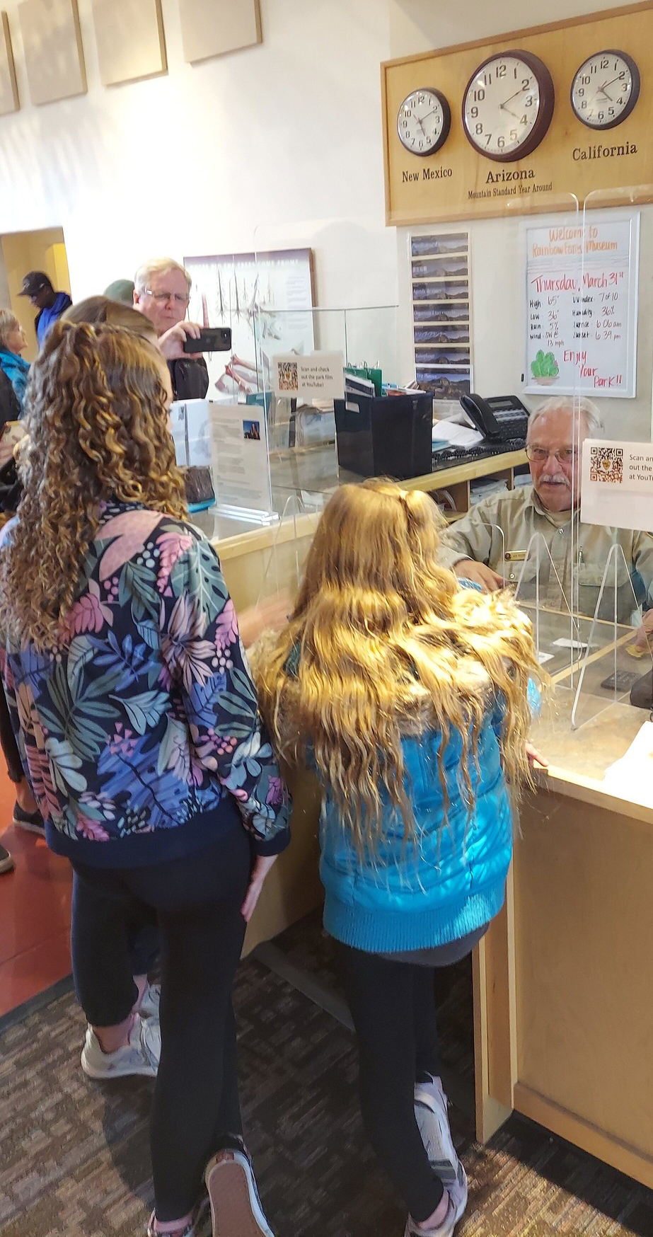 Many people including a uniformed man inside a busy building.