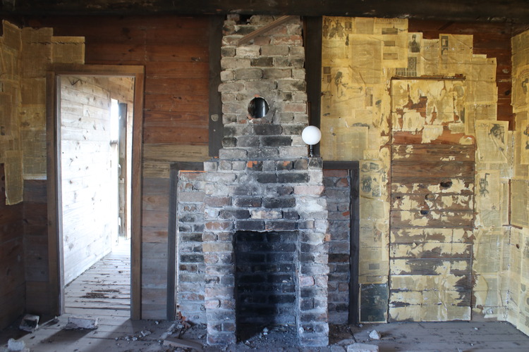 Wooden interior room with small brick fireplace.
