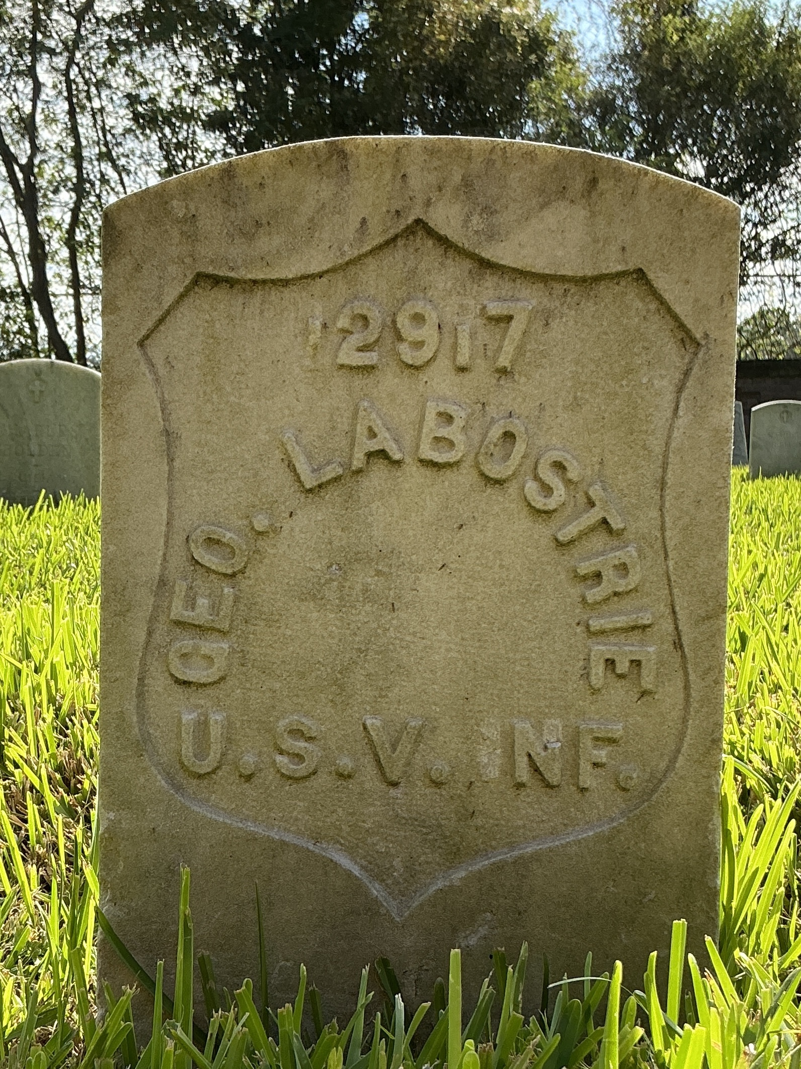 Front of historic upright marble headstone with recessed shield face.
