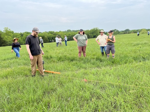 a group of people operating equipment in a field.
