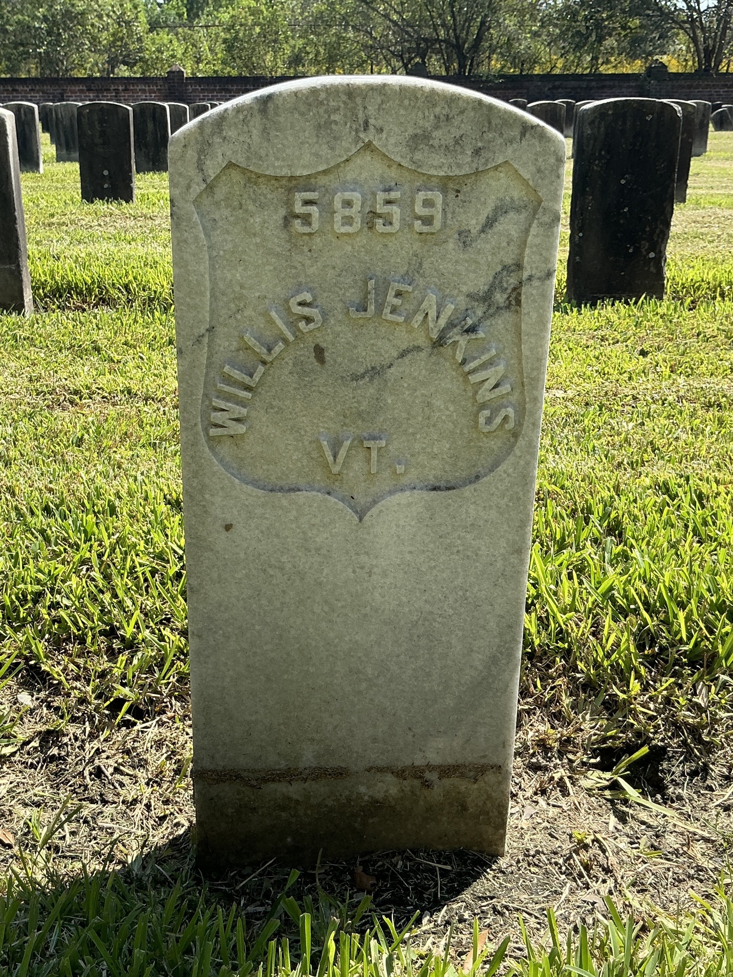 Front of historic upright marble headstone with recessed shield face.