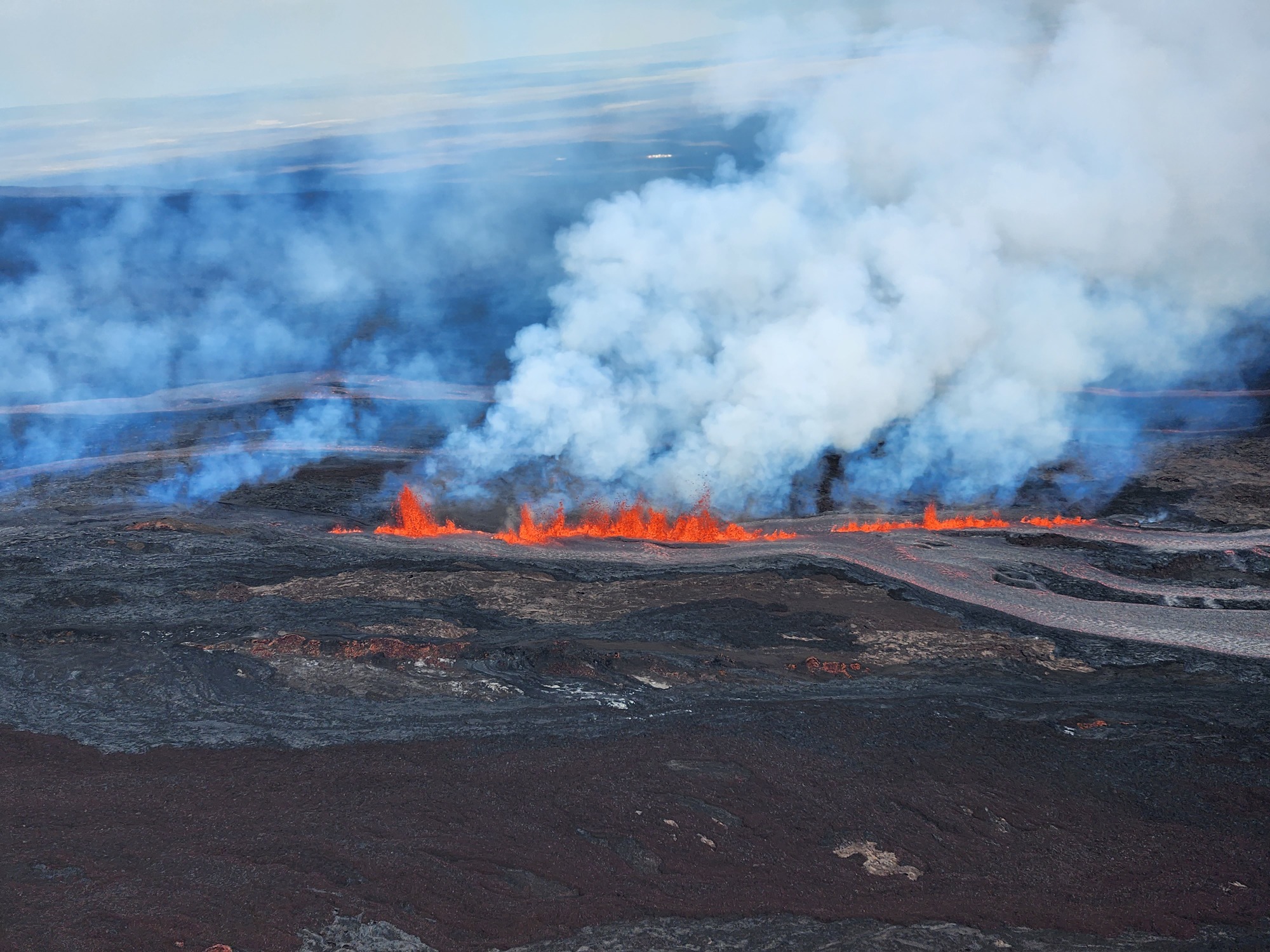 Channelized rivers of lava flows downslope from tall fountains of lava.