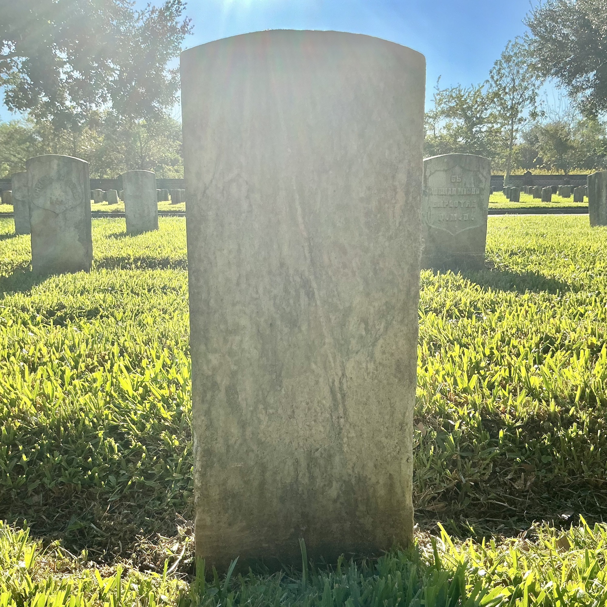 Back of historic upright marble headstone with recessed shield face.