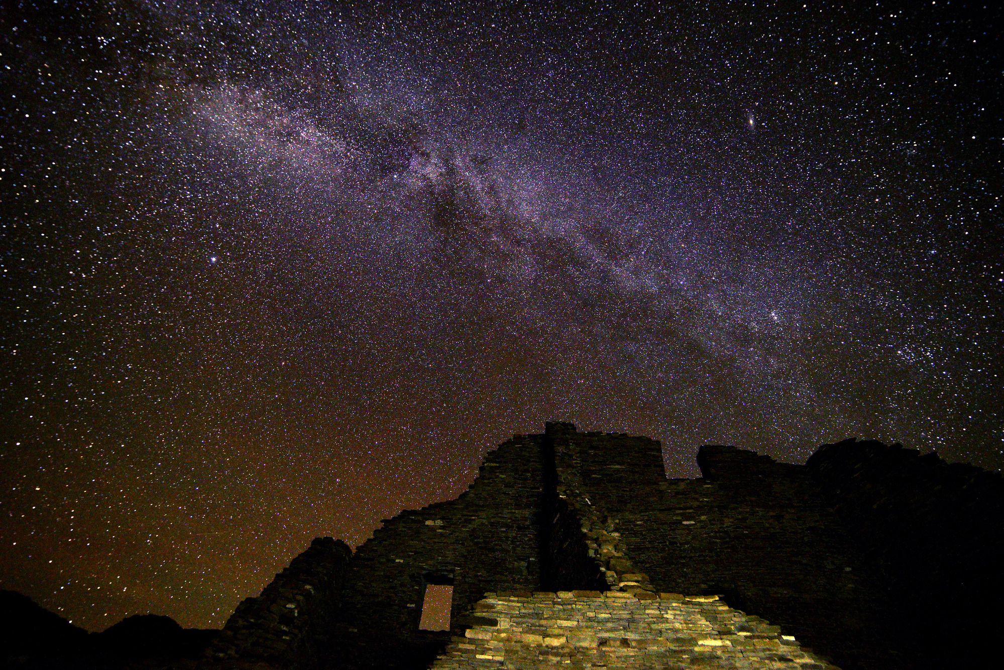 The Milky Way and stars fill the night sky above an Ancestral Puebloan ruin at Chaco Culture National Historical Park, New Mexico.        
