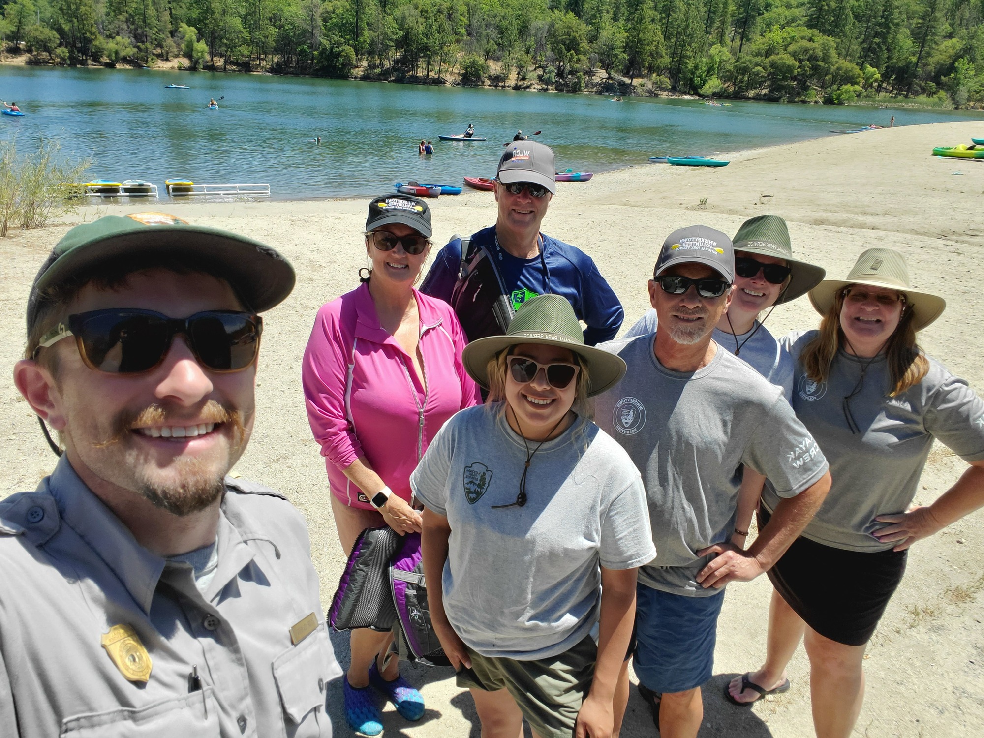 Volunteers and rangers pose for a groups photo with Whiskeytown Lake behind them.NPS