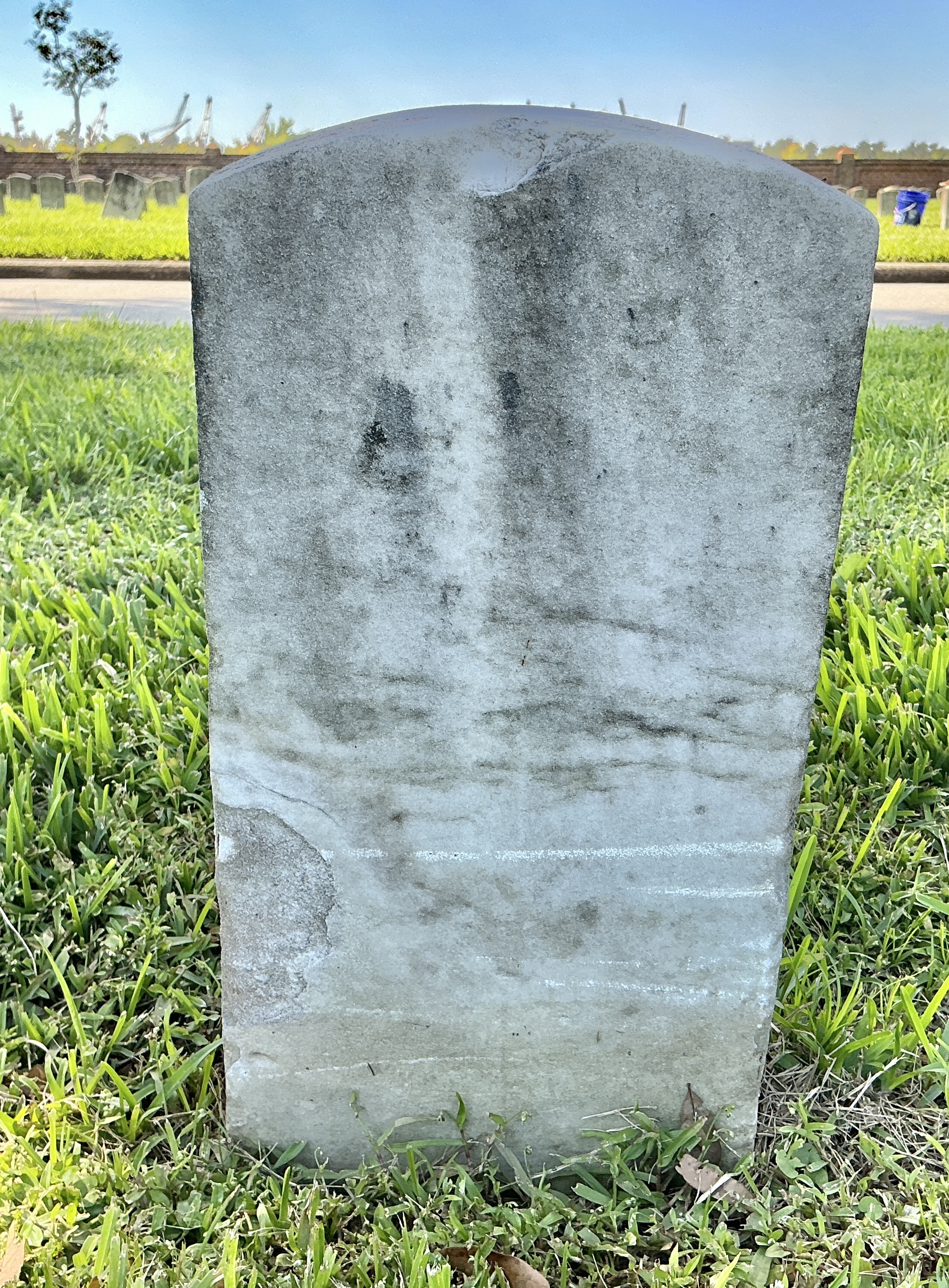 Back of historic upright marble headstone with recessed shield face.