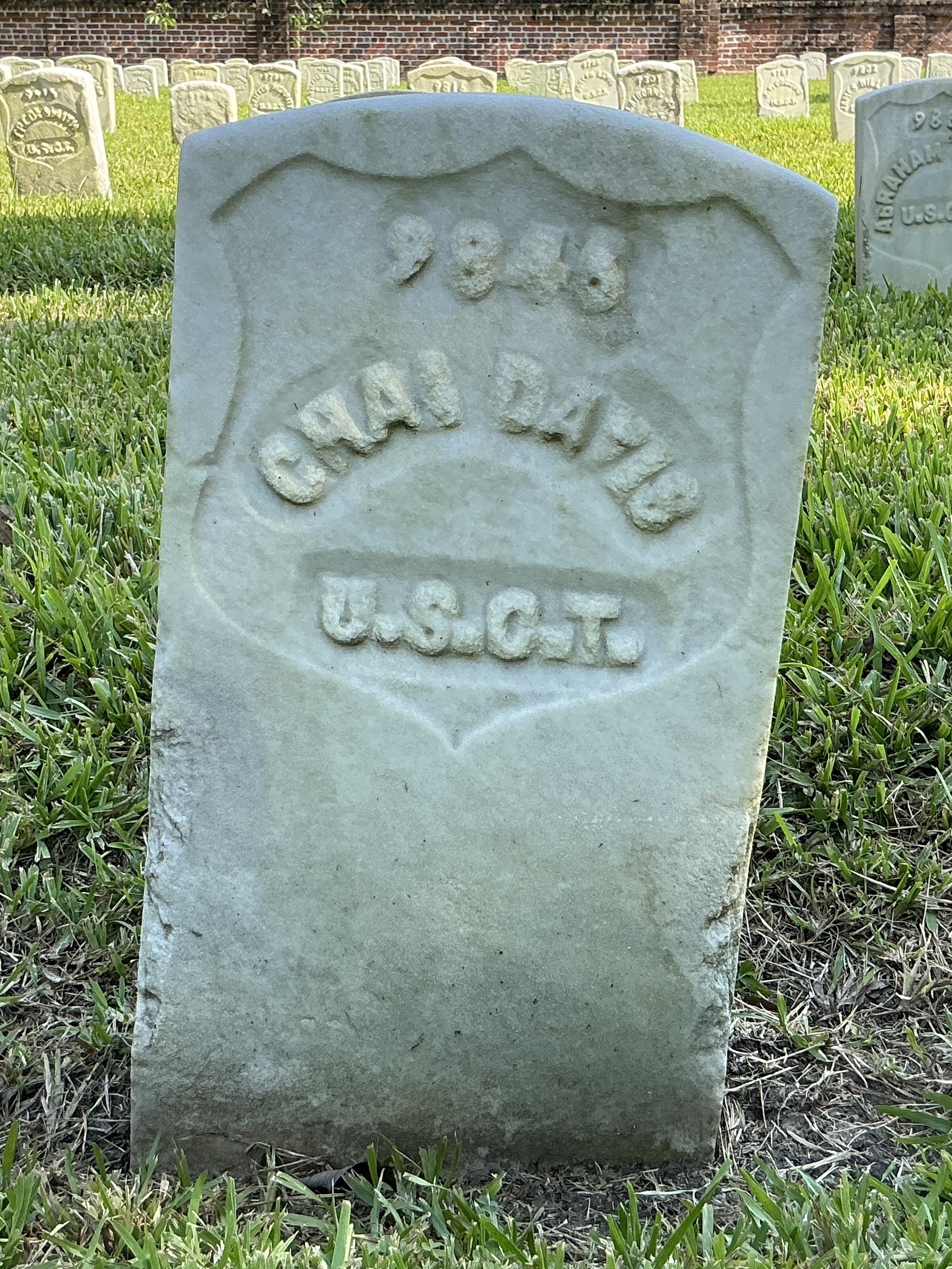 Front of historic upright marble headstone with recessed shield with recessed lettering face.