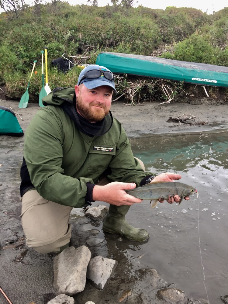 man holds a greyling fish