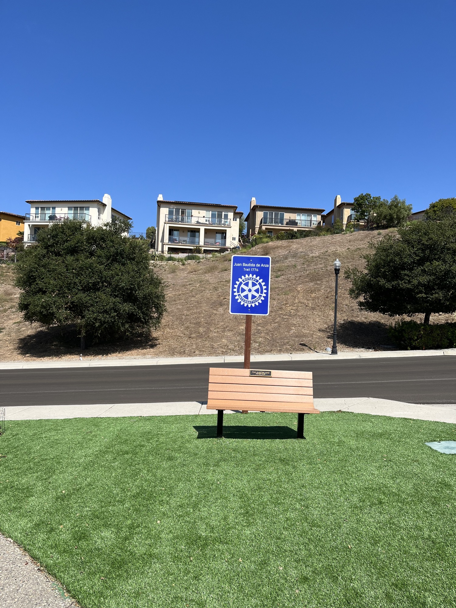 Sign reading Juan Bautista de Anza Trail 1776 Rotary International behind a wooden bench