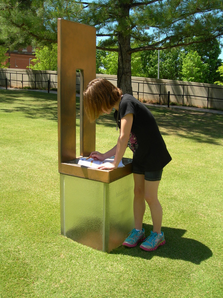 A little girl is working on her Junior Ranger Activity book on one of the empty chairs.