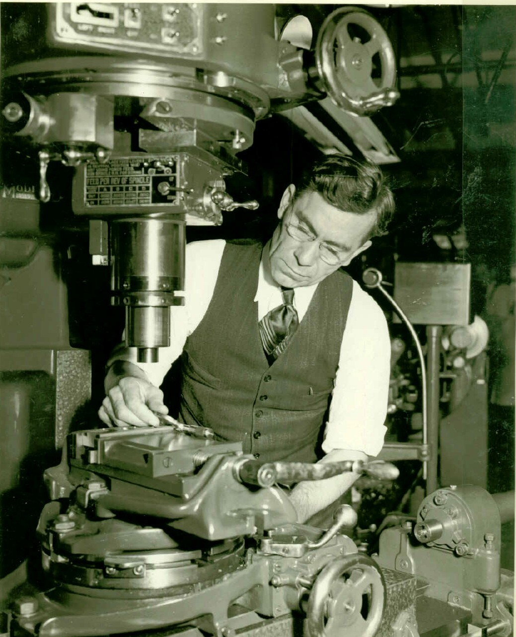 Black and white photograph of man using machinery.