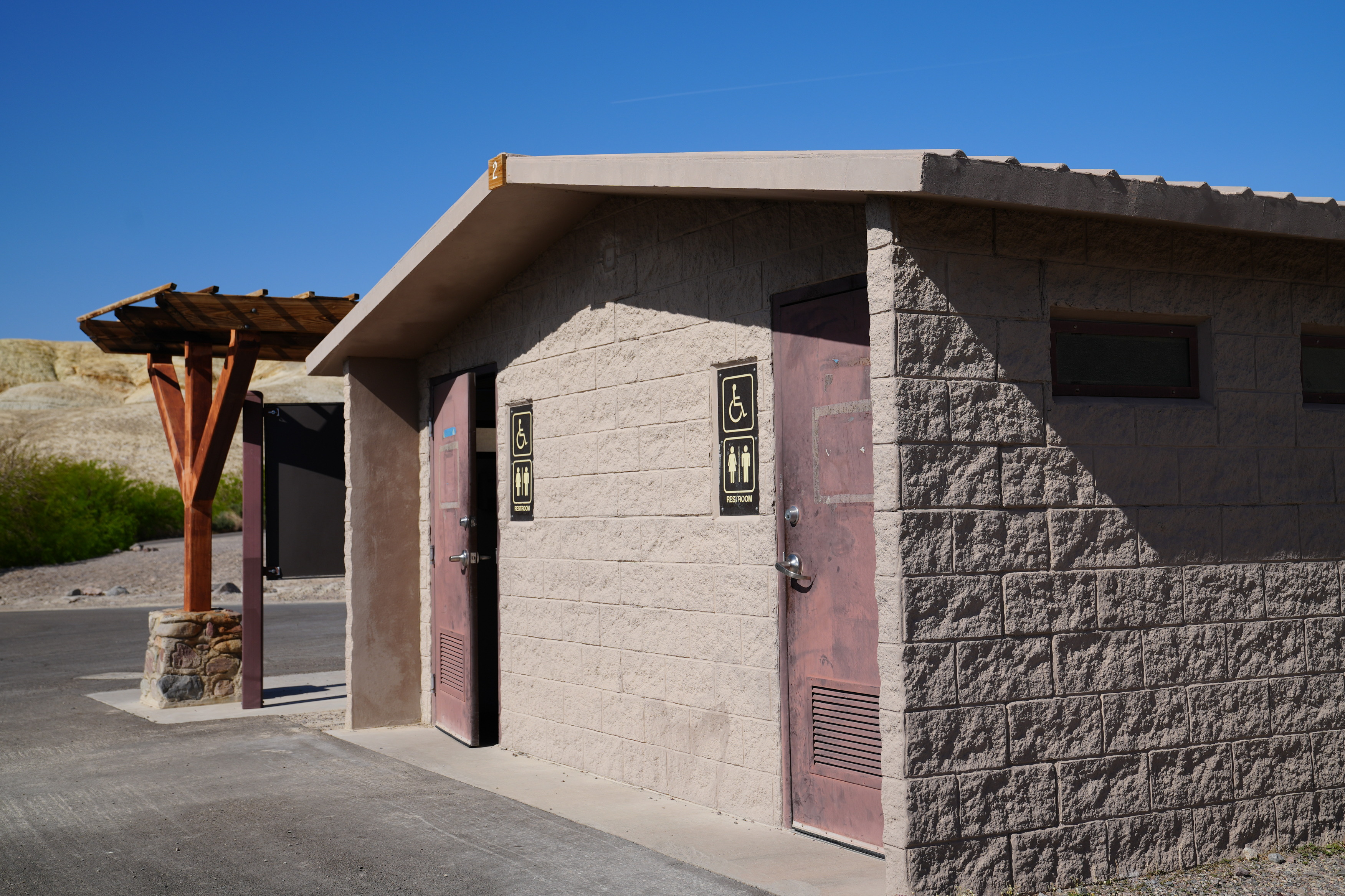Establishing shot showing the outside of the Texas Springs Upper Loop bathrooms; The entryway is flat to enter the bathrooms 