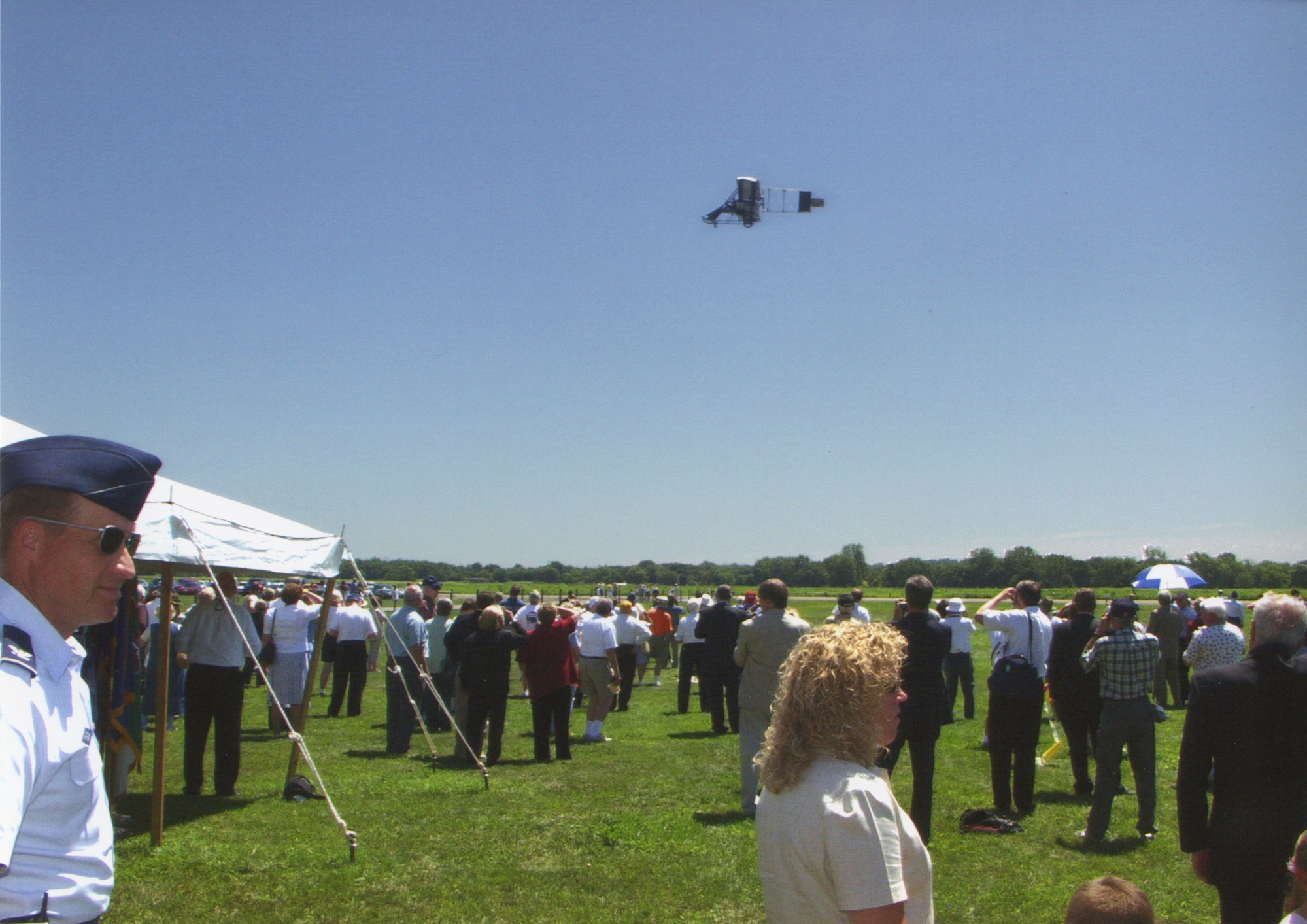 Replica airplane flying above crowd 