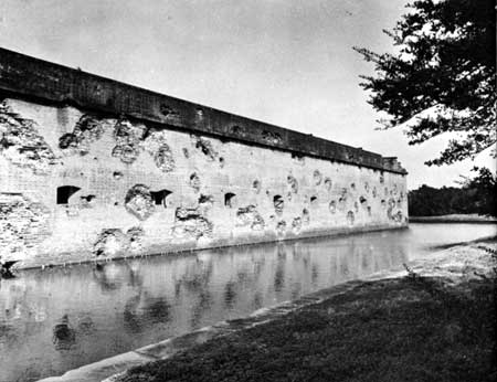 Pot marked brick wall, with a moat in front of it. 