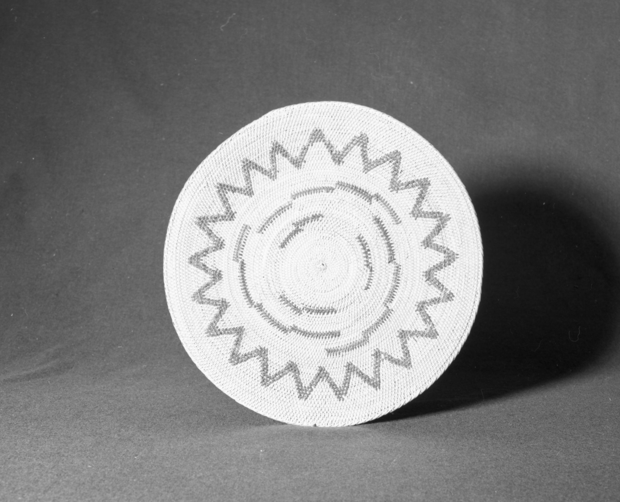 Marie Rozier Collection, Catalog No. 34. Object: Miwok sifting tray. Dimensions: 15 x 1". Materials: split redbud, fern root, split shoots (maple), grass bundle foundation. Technology: leftward coil direction; moving ends flipped to left and caught by next stitch or trimmed on work face; fag ends trimmed on back face or flipped over and concealed by successive rows of stitching. Collection History: bought from Mrs. Louise Fuentes. Catalogued by Craig Bates and Barbara Beroza. Yosemite Collections, National Park Service.