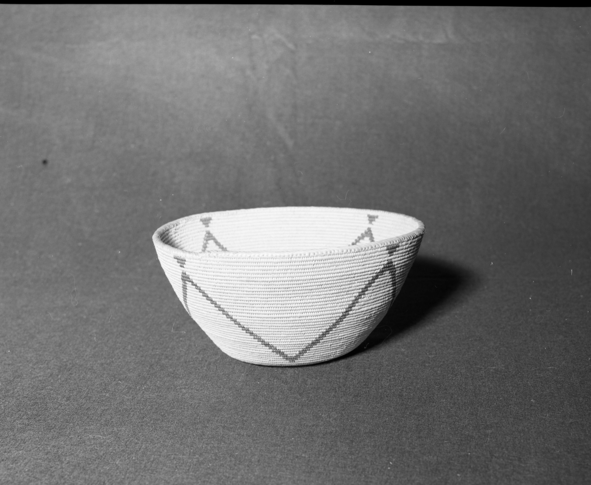 Mrs. Donald Segerstrom Collection. Object: Miwok or Paiute (?) basket. Dimensions: 9 1/4 x 4 1/2". Materials: Willow, bracken fern root. Technology: Interlocking stitch, leftward coil direction, fag ends trimmed on work face, moving ends trimmed on interior, rim overstitched in opposite direction of the way in which the basket is made. Photographed by Michael Dixon. Catalogued by Craig Bates and Barbara Beroza. Yosemite Collections, National Park Service. 1/83.