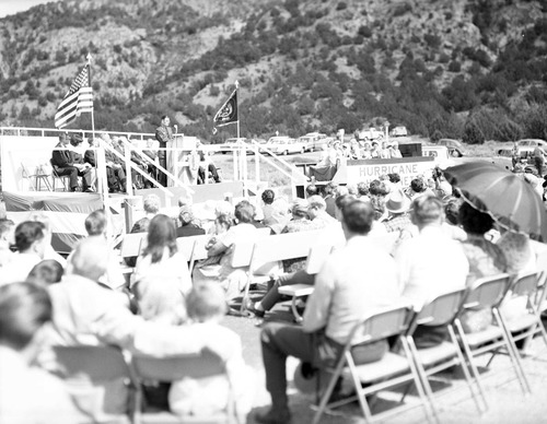 Warren F. Hamilton, Superintendent of Zion National Park, addressing visitors from podium at dedication of Taylor Creek road (Kolob Canyons). Note Hurricane Harmonetts [Harmonettes] singing group at right.