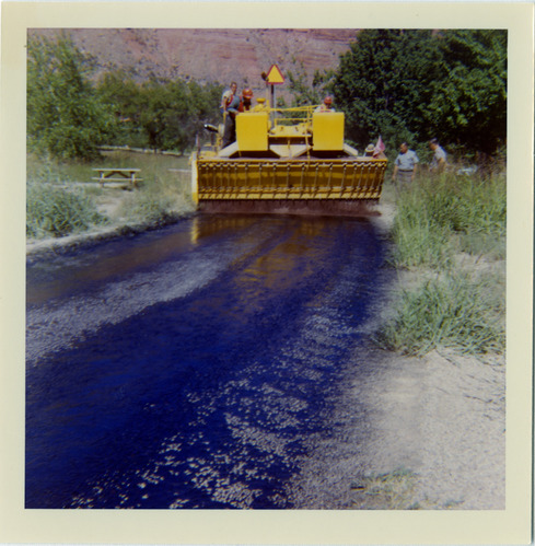 Workers operating chipsealing machine to chipseal roads.