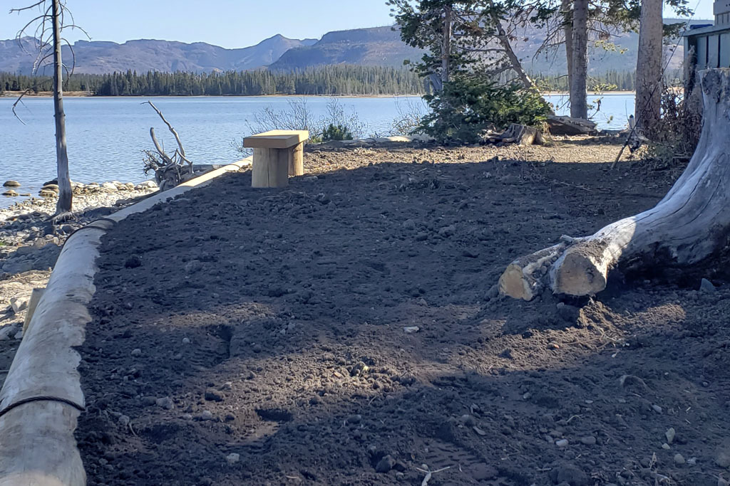 A brand-new retaining wall near a cabin on a lake shore.