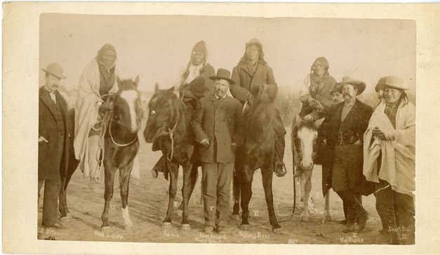 Group of Men, Some Mounted Others on Foot Wearing Coats or Wrapped in Blanket