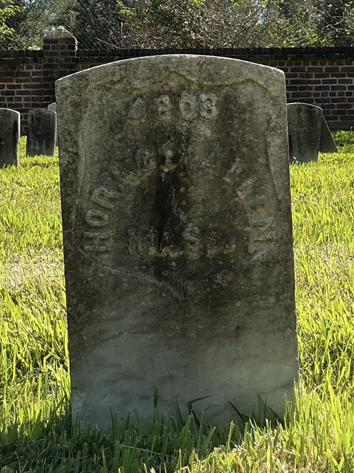 Front of historic upright marble headstone with recessed shield face.