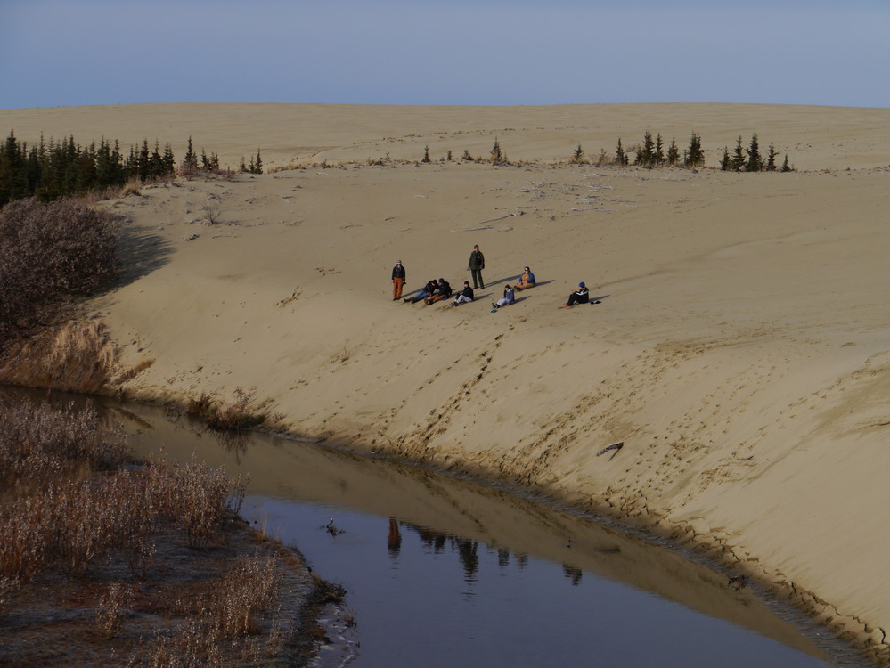 students sitting on a sand dune