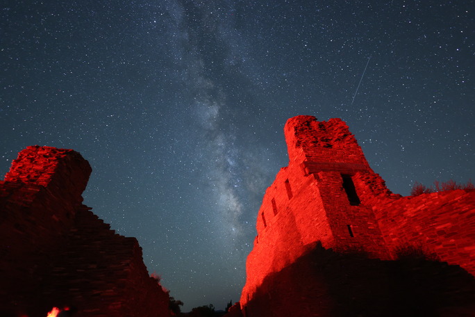 Milky Way in a starry sky with red sandstone church remnants in the foreground.