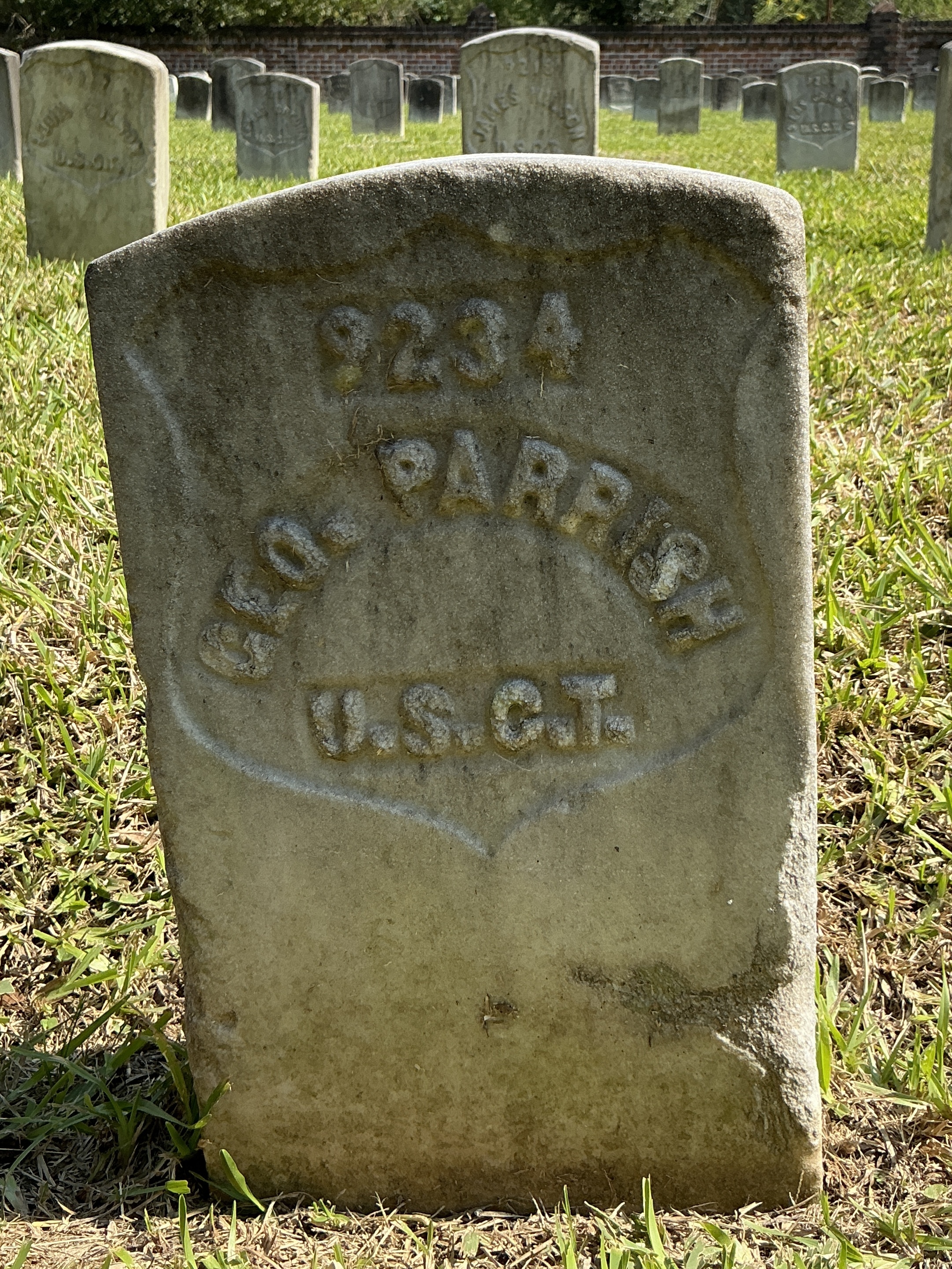 Front of historic upright marble headstone with recessed shield with recessed lettering face.