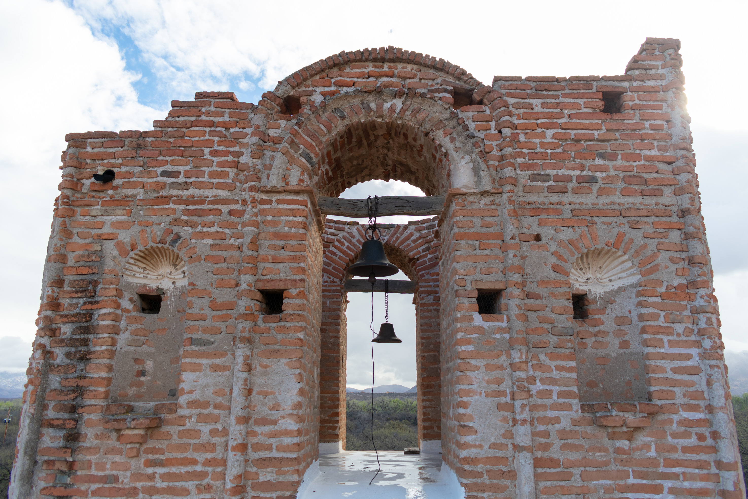 burnt brick with mortar and copper bell hanging from post