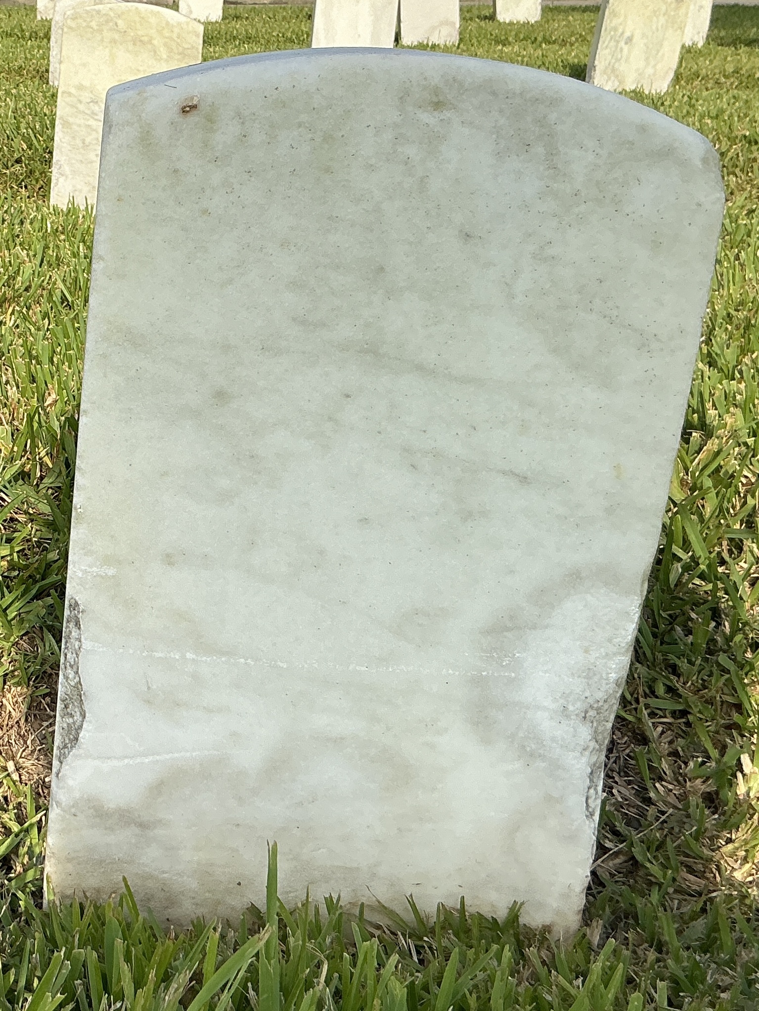 Back of historic upright marble headstone with recessed shield face.