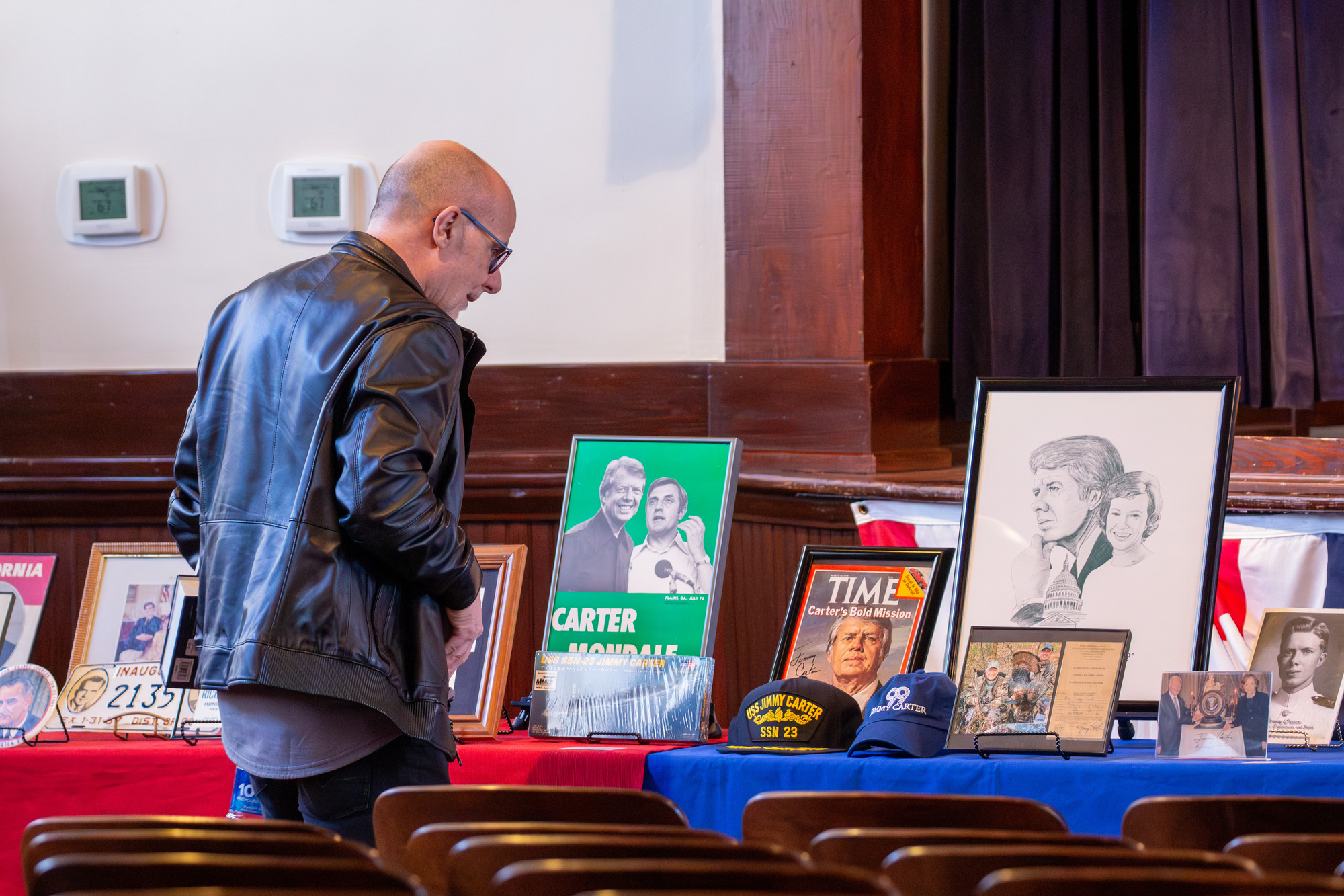 Man looking at presidential memorabilia on table. 