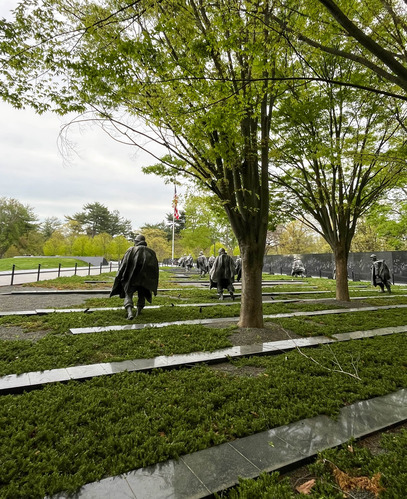 Statues of Korean War soldiers marching towards the U.S. flag on a rainy day