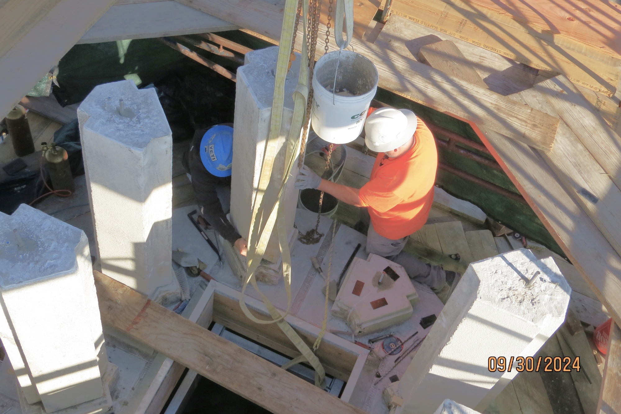Worker stands by columns taller than him and arranged in a circle. He puts the column in place.