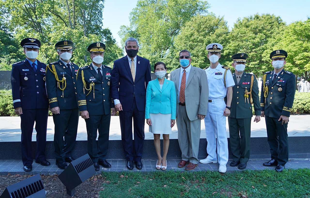 Servicemen posing in front of Korean War Veterans Memorial with civilians. 
