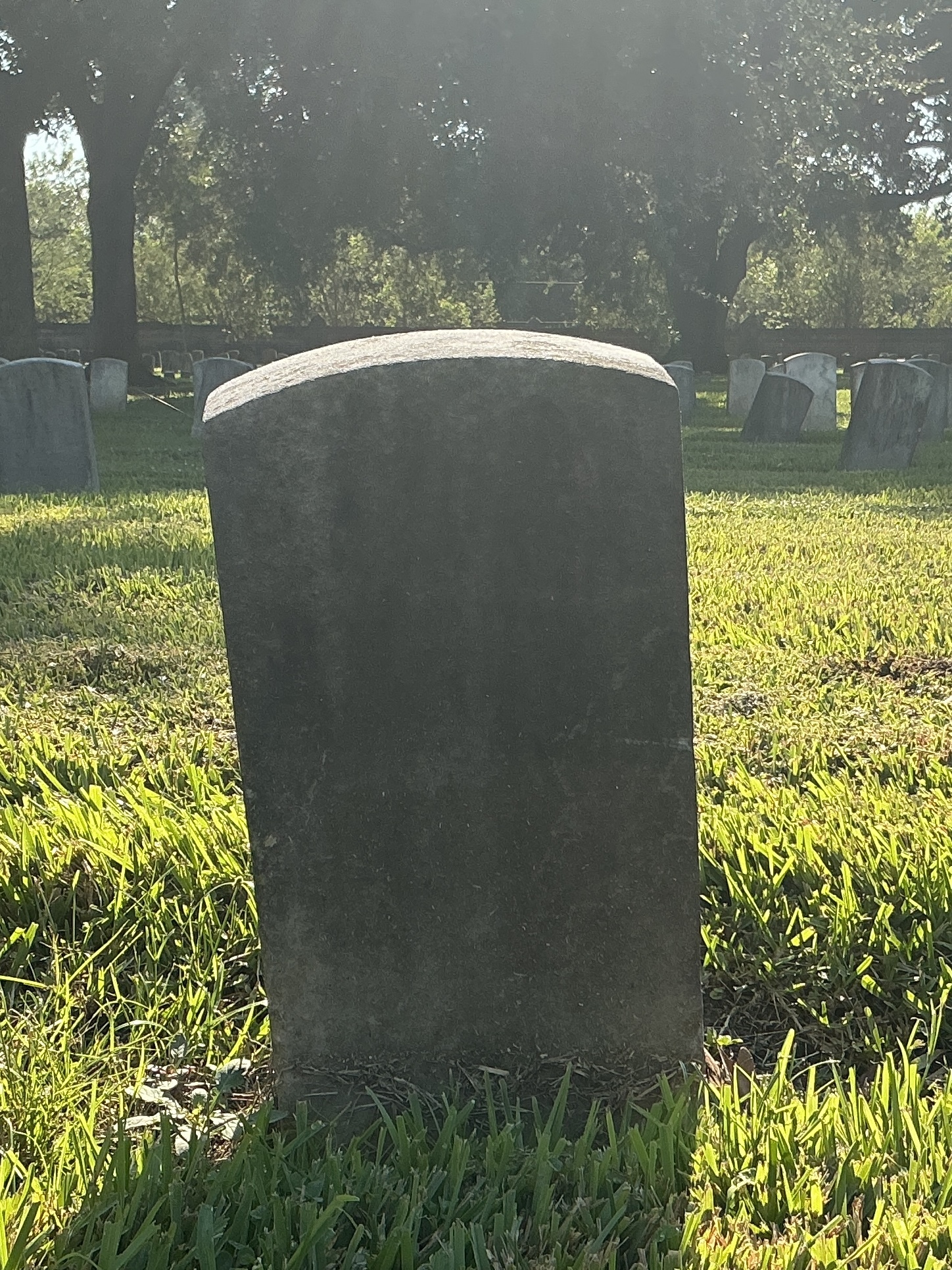 Back of historic upright marble headstone with recessed shield face.