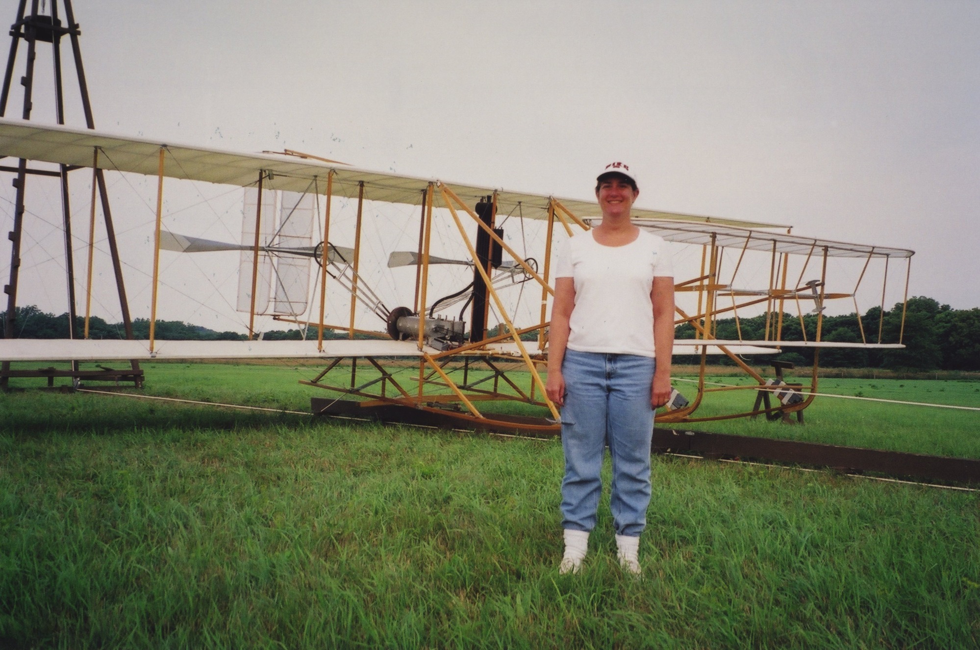A woman stands in front of reconstructed historic aircraft