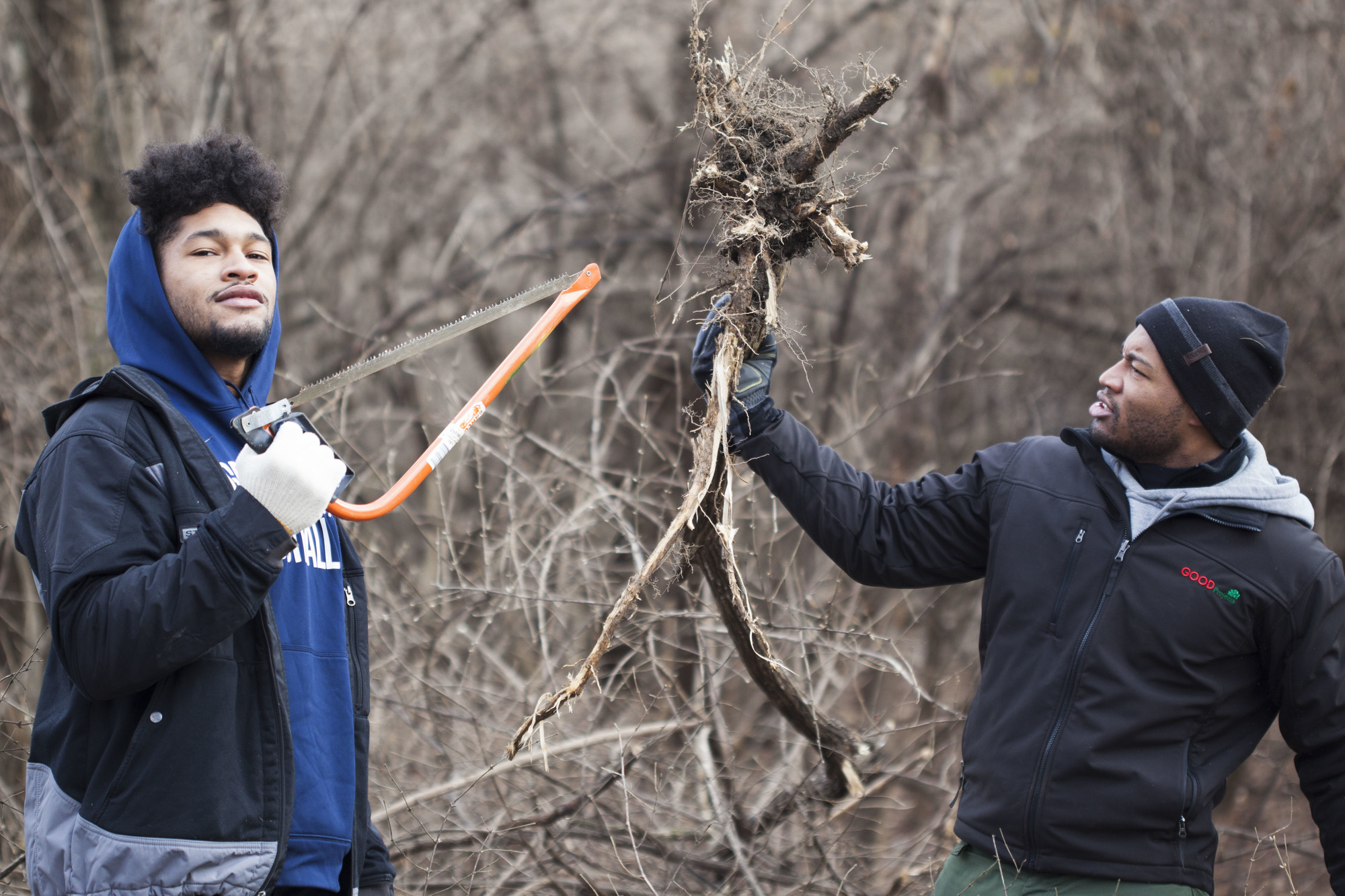 Two volunteers pose with a root they removed from the ground.