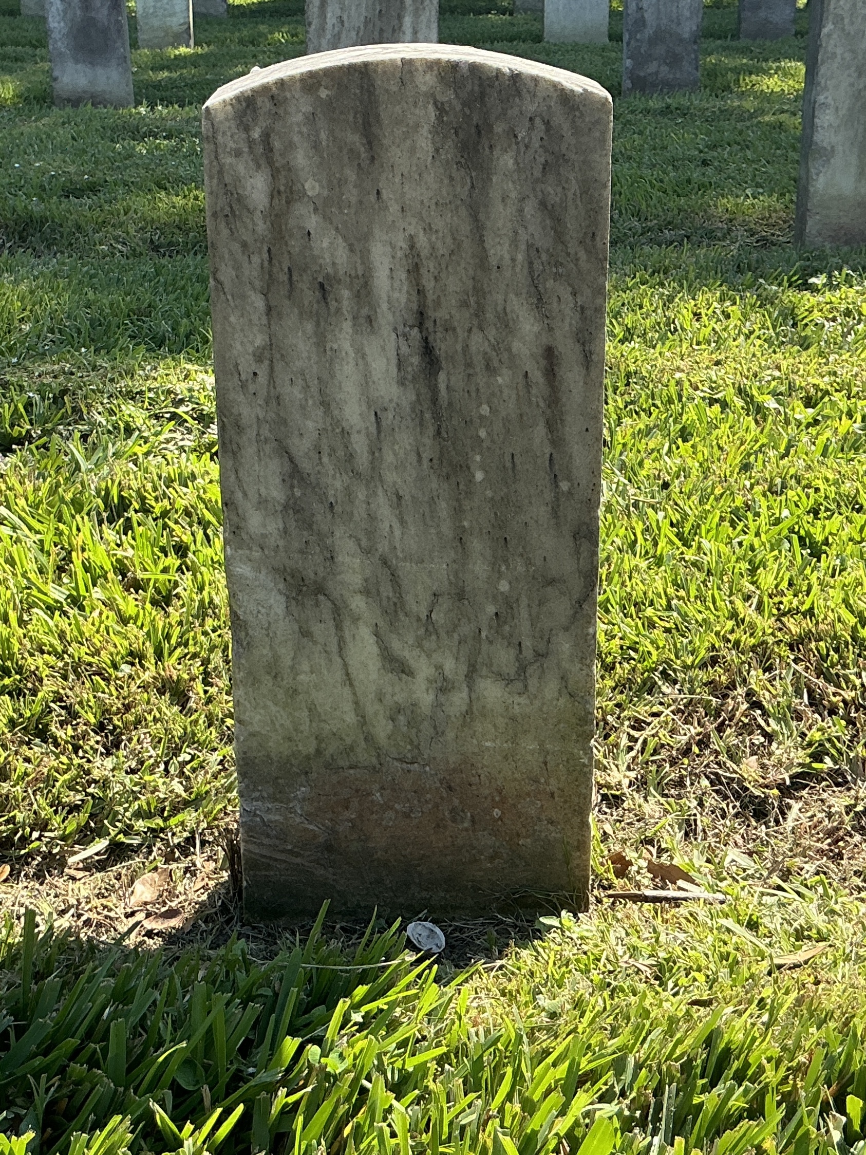 Back of historic upright marble headstone with recessed shield face.