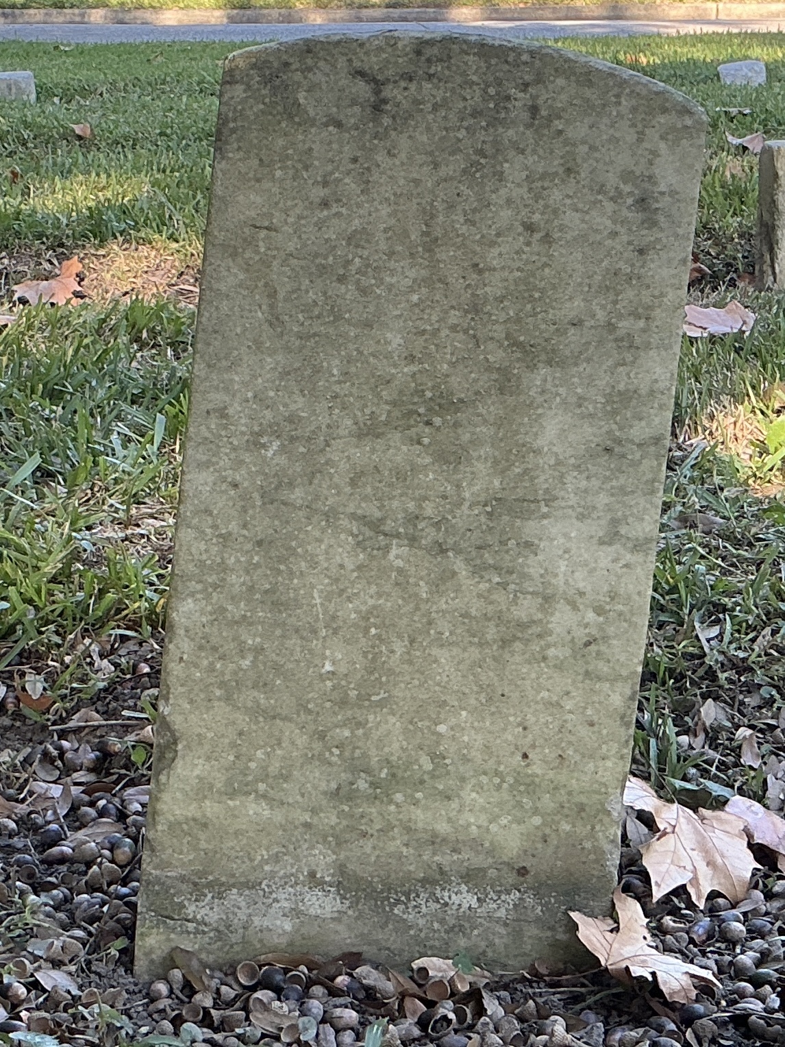 Back of historic upright marble headstone with recessed shield face.