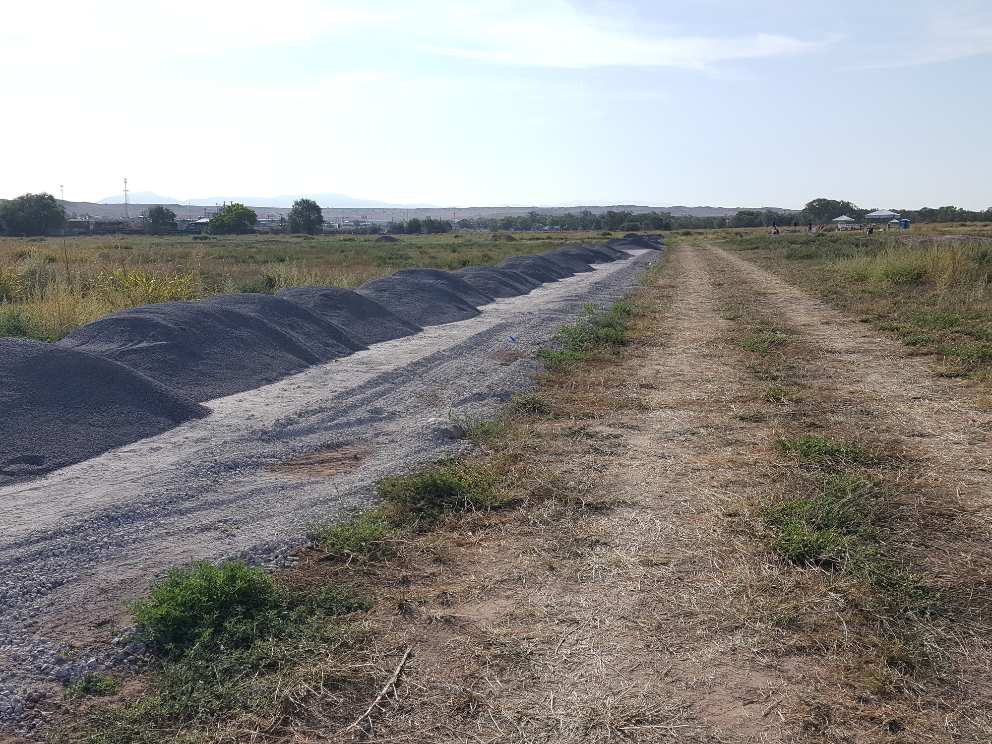 A dirt road next to a pile of sand.