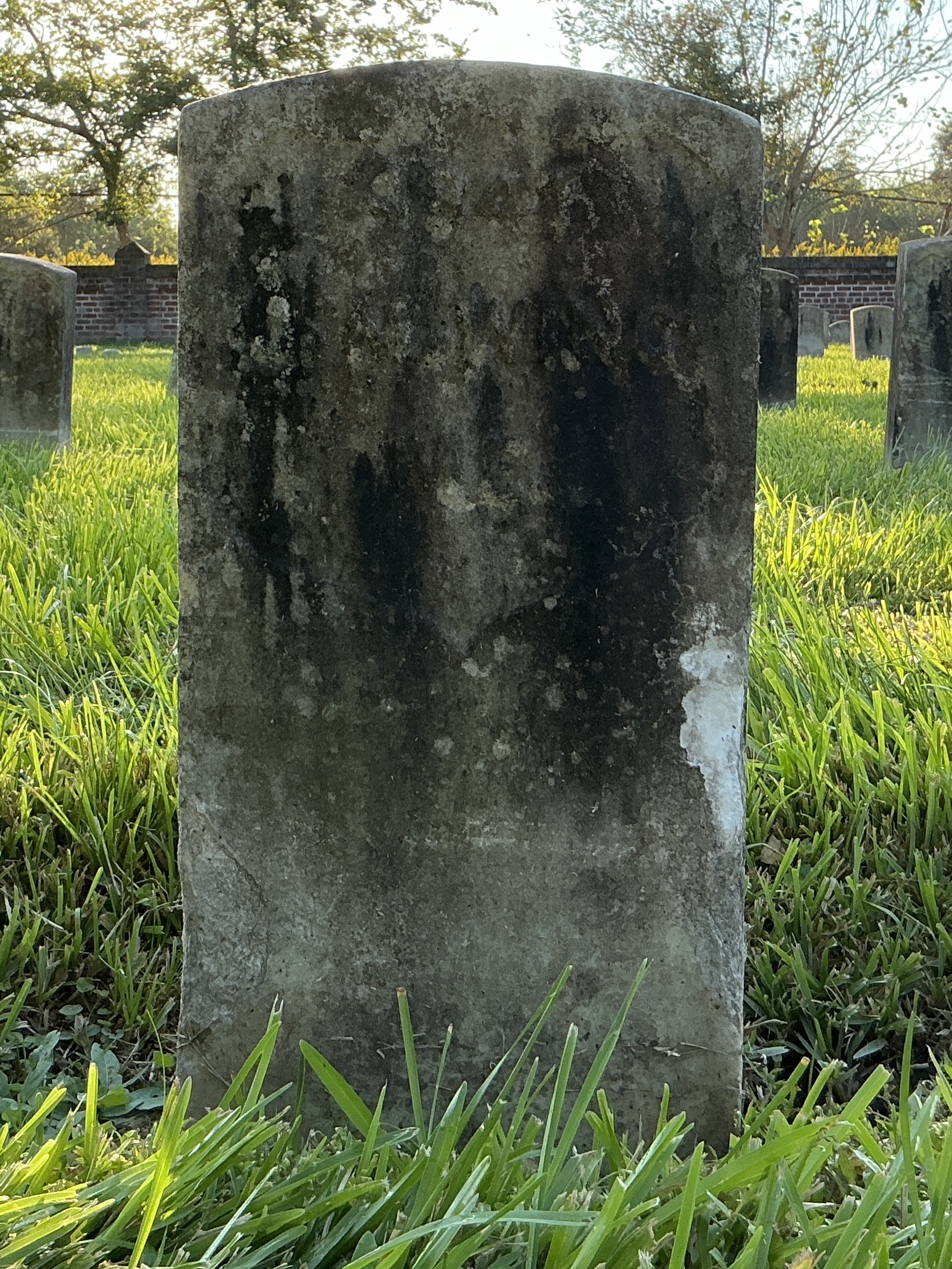 Front of historic upright marble headstone with recessed shield face.