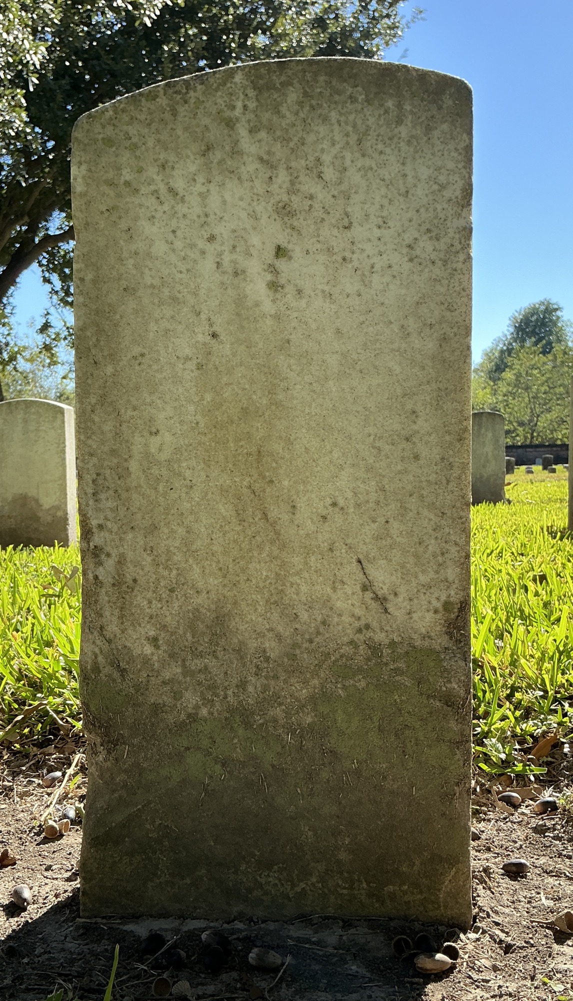Back of historic upright marble headstone with recessed shield face.