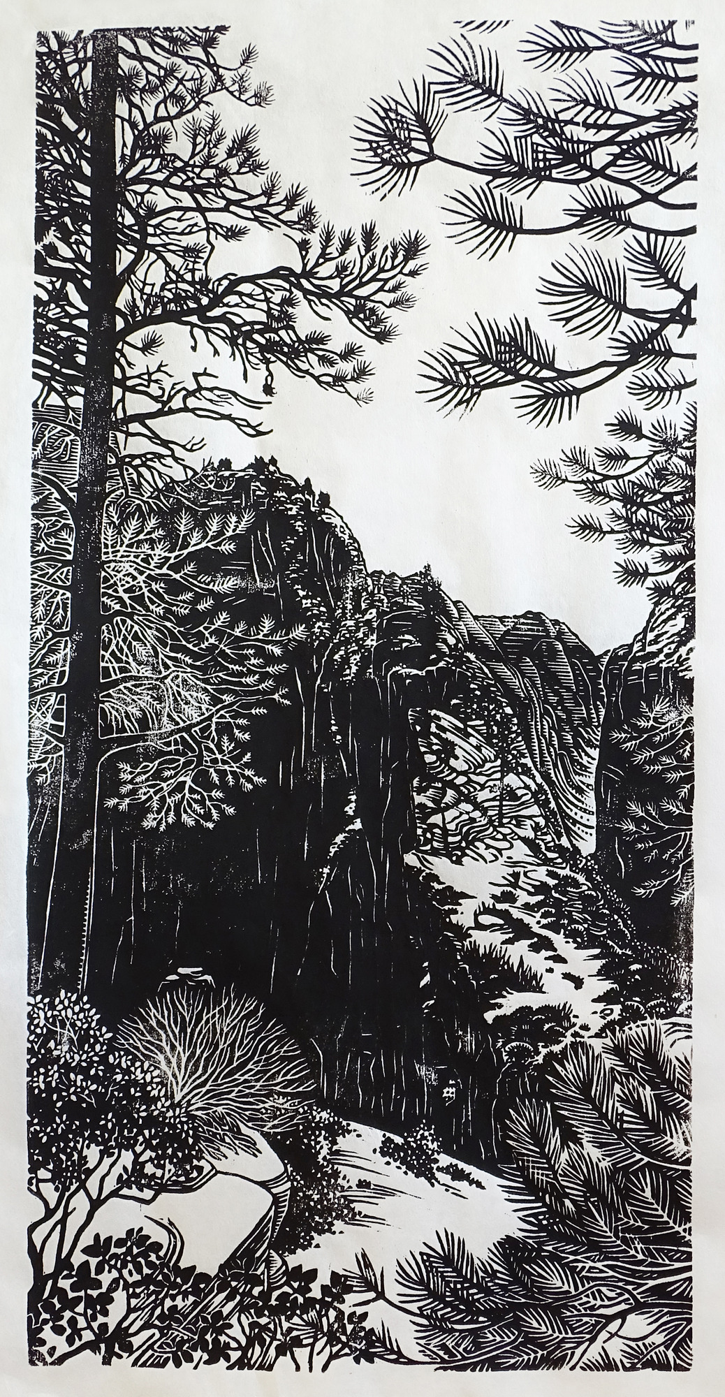 A black-and-white image made with ink on paper.  In the middleground, tall black sandstone cliffs stand above a canyon. In the very center of the image, a white trail follows a ridge up to Angels Landing (a tall peak). In the far background, more black cliffs rise under a white sky. In the foreground, black trees and shrubs dot the white sandstone landscape.