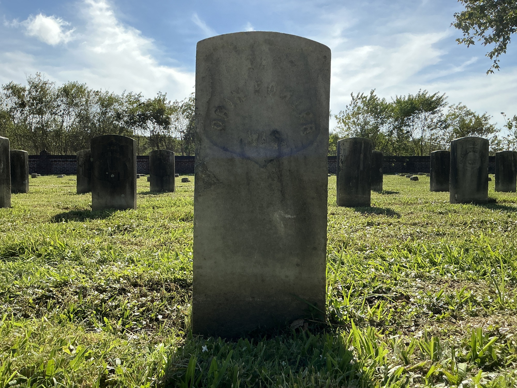 Front of historic upright marble headstone with recessed shield face.