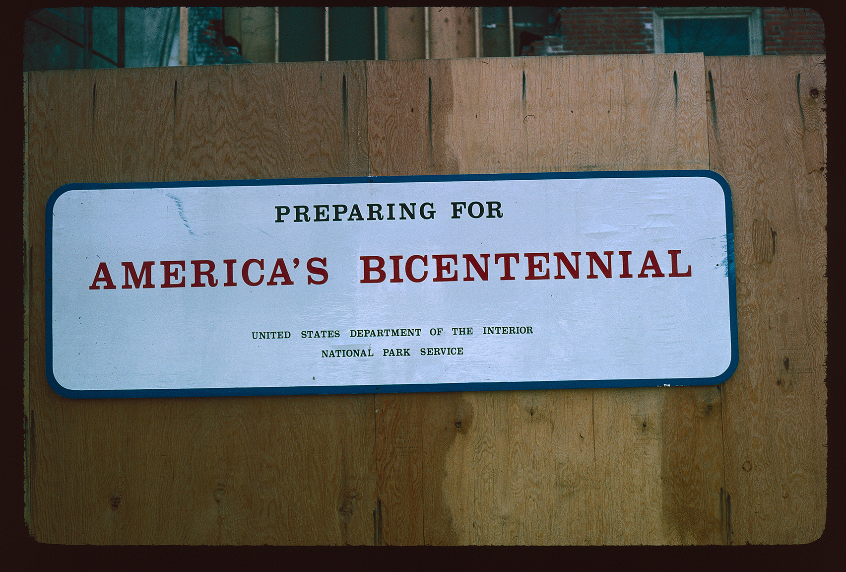 Park Service sign on wood construction fence. "Preparing For America's Bicentennial".